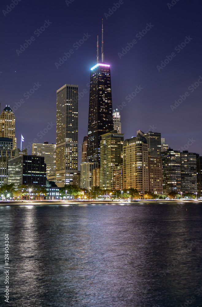 Big city skyline along water with skyscrapers at night