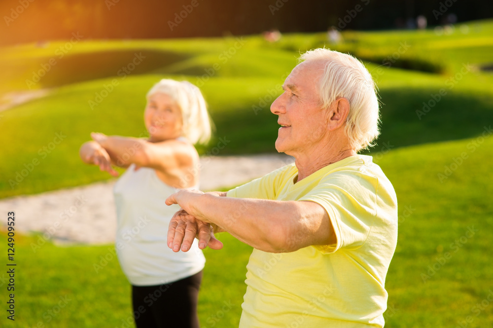 Senior man does exercise. Elderly guy outdoors. How to strengthen the organism. Way to health.