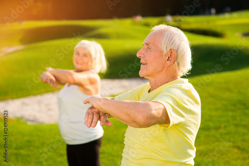 Senior man does exercise. Elderly guy outdoors. How to strengthen the organism. Way to health.