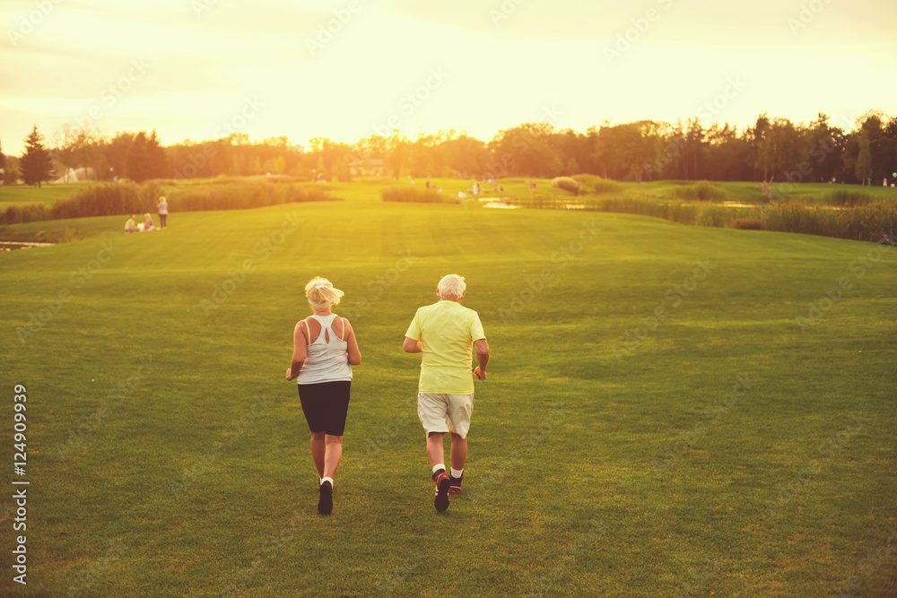 Senior couple is jogging. People running on grass. Health of respiratory system. Do cardio every day. Senior couple is jogging. People running on grass. Health of respiratory system. Do cardio every day.