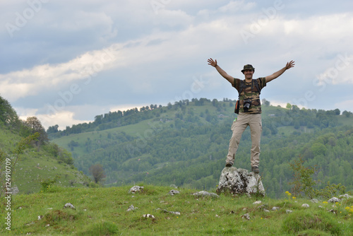 Happy landscape travel photographer on a mountain hill with green landscape in the background