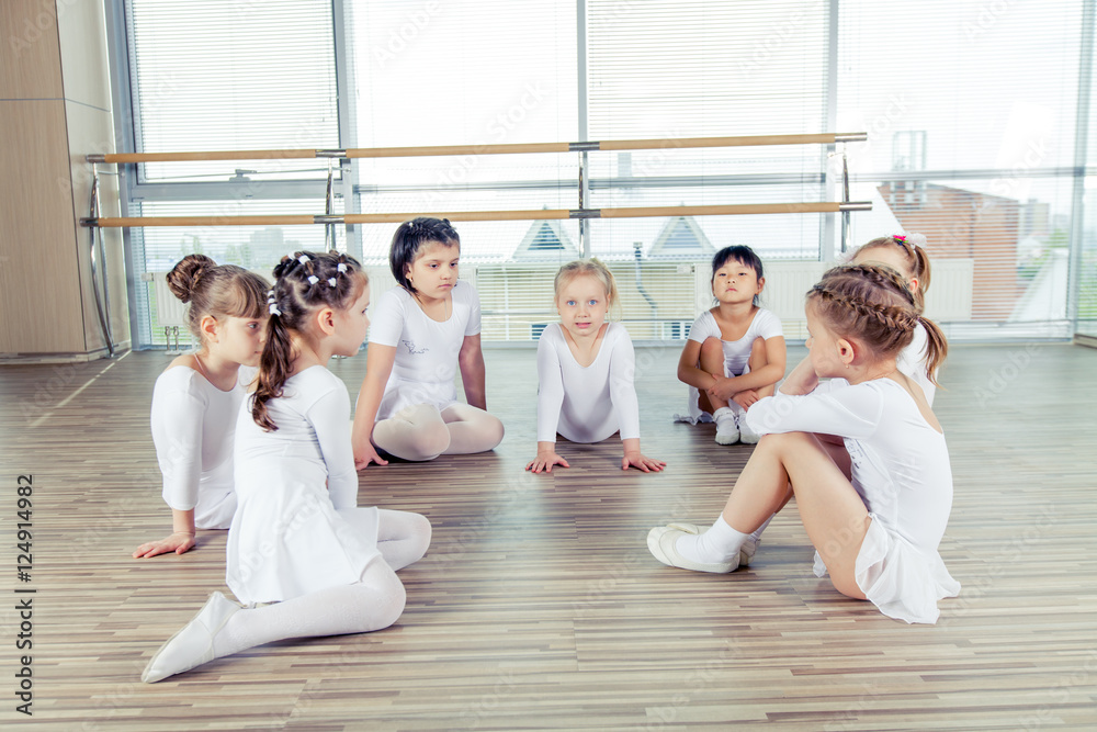 Fototapeta premium group of seven little ballerinas sitting on the floor. They are 