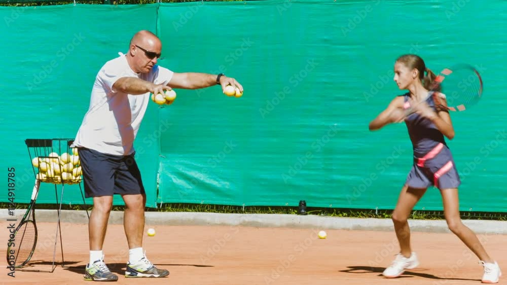 Instructor or coach teaching child how to play tennis on a court indoor Instructor or coach teaching child how to play tennis on a court indoor