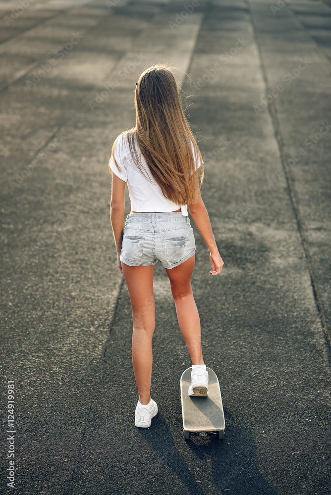 Cute beautiful young and sexy girl in a white T-shirt, shorts and sneakers  ride a skateboard Stock Photo | Adobe Stock