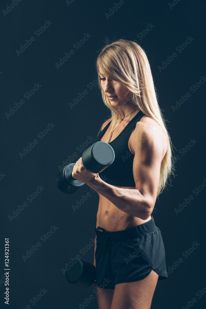 Athletic woman with dumbbells on a dark background Athletic woman with dumbbells on a dark background