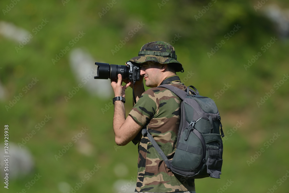 Fototapeta premium Landscape professional photographer taking a picture in nature with green blurry background
