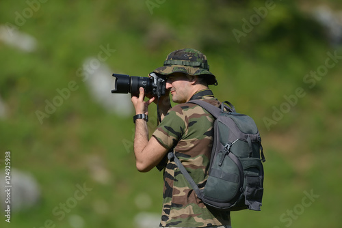 Landscape professional photographer taking a picture in nature with green blurry background