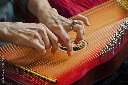 Playing music on lap harp in closeup view/Close-up of playing lap harp made out of redwood with carved tree