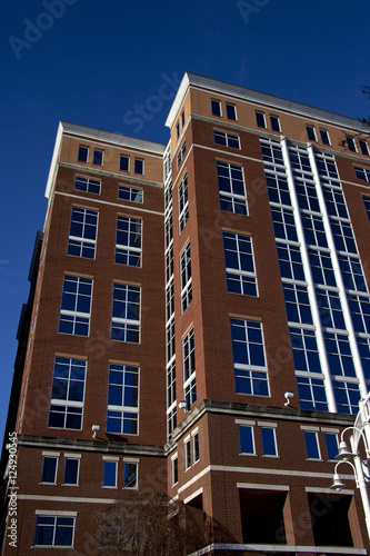 Tall brick building with blue tinted windows coverd on two sides with clear blue sky