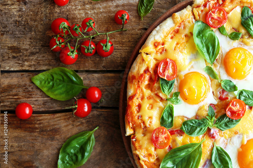 Margarita pizza with basil leaves and egg on wooden background
