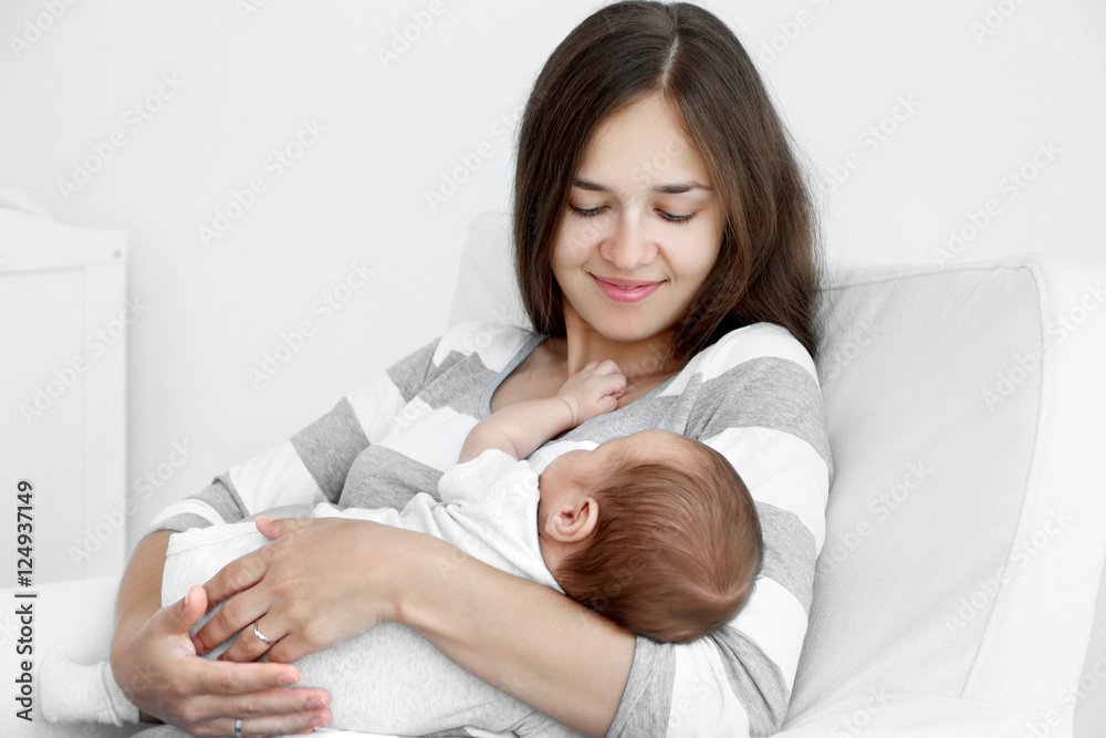 Portrait of pretty young woman holding sleeping baby at home Portrait of pretty young woman holding sleeping baby at home