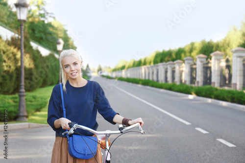 Young woman with bicycle in park on blurred background