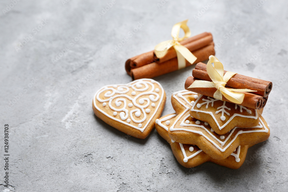 Tasty gingerbread cookies and cinnamon sticks on textured background Tasty gingerbread cookies and cinnamon sticks on textured background