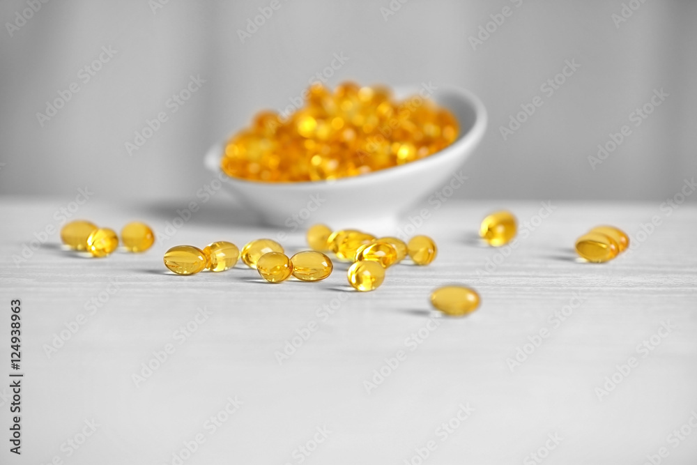 Cod liver oil capsules on white wooden table Cod liver oil capsules on white wooden table