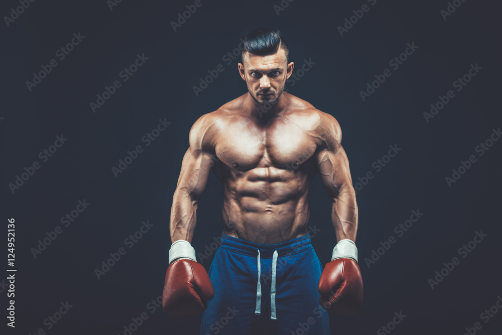 Fototapeta premium Muscular boxer in studio shooting, on black background.