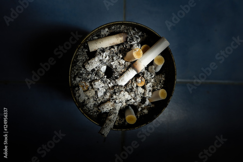 The ash of cigarettes on the ashtray. Dark tone low key.