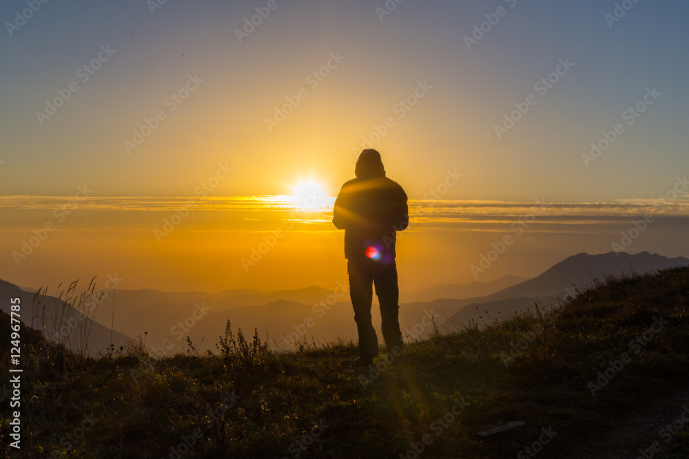 Silhouette of one young man standing at the mountain top
