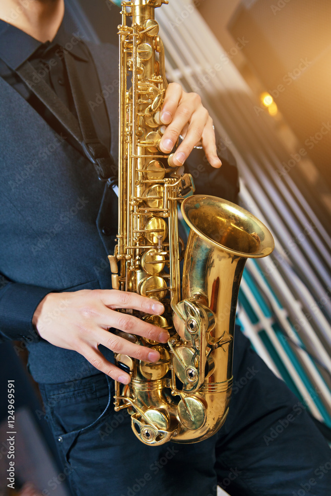 Obraz premium Musical instrument saxophone close-up. Hands on a musical instrument. Young guy playing jazz.