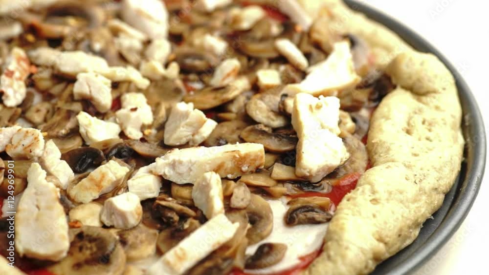 Closeup of chicken and mushroom pizza being sprinkled with Italian herbs on top, slow motion Closeup of chicken and mushroom pizza being sprinkled with Italian herbs on top, slow motion