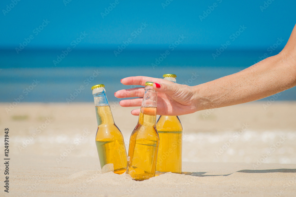 Ice cold beer bottles in the sand under the sun Ice cold beer bottles in the sand under the sun