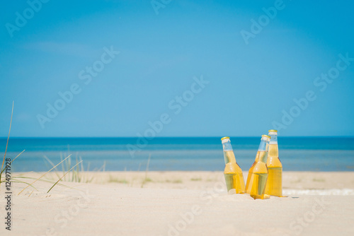 Ice cold beer bottles in the sand under the sun