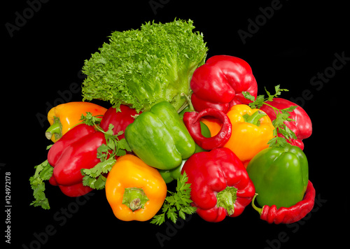 Several green, yellow and red bell peppers among the greens