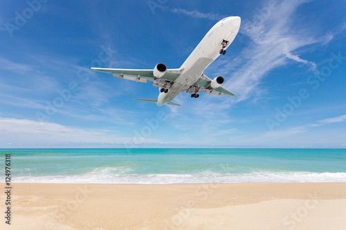Airplane landing above beautiful beach and sea background.