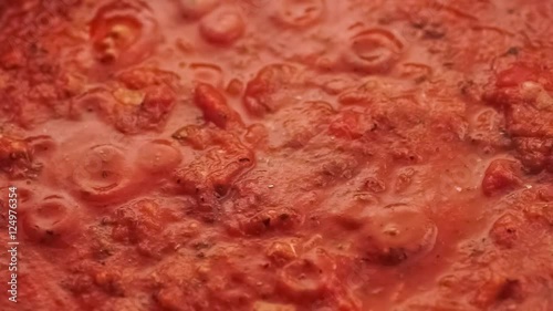 Gourmet fresh sliced field mushrooms added to simmering red tomato pasta sauce and mixed with spoon, closeup slow motion