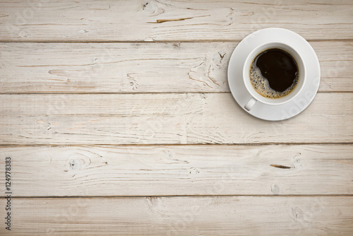 Coffee cup with saucer on wooden planks background, top view photo