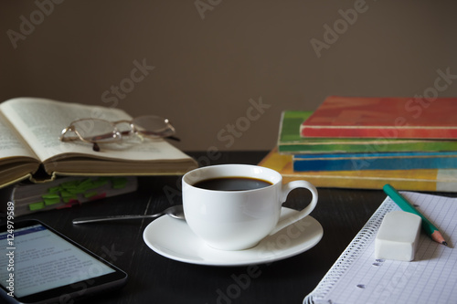 Coffee in front of textbooks,smartphone and notebook on a dark w