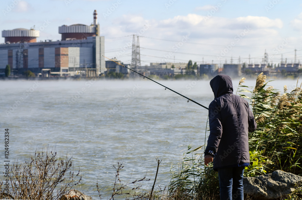 fisherman on the background of the nuclear power plant