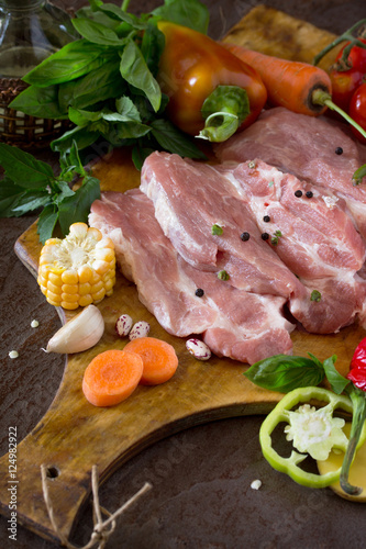 Fresh raw meat pork fillet with vegetables on the cutting board.