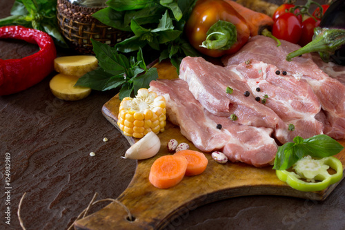 Fresh raw meat pork fillet with vegetables on the cutting board.