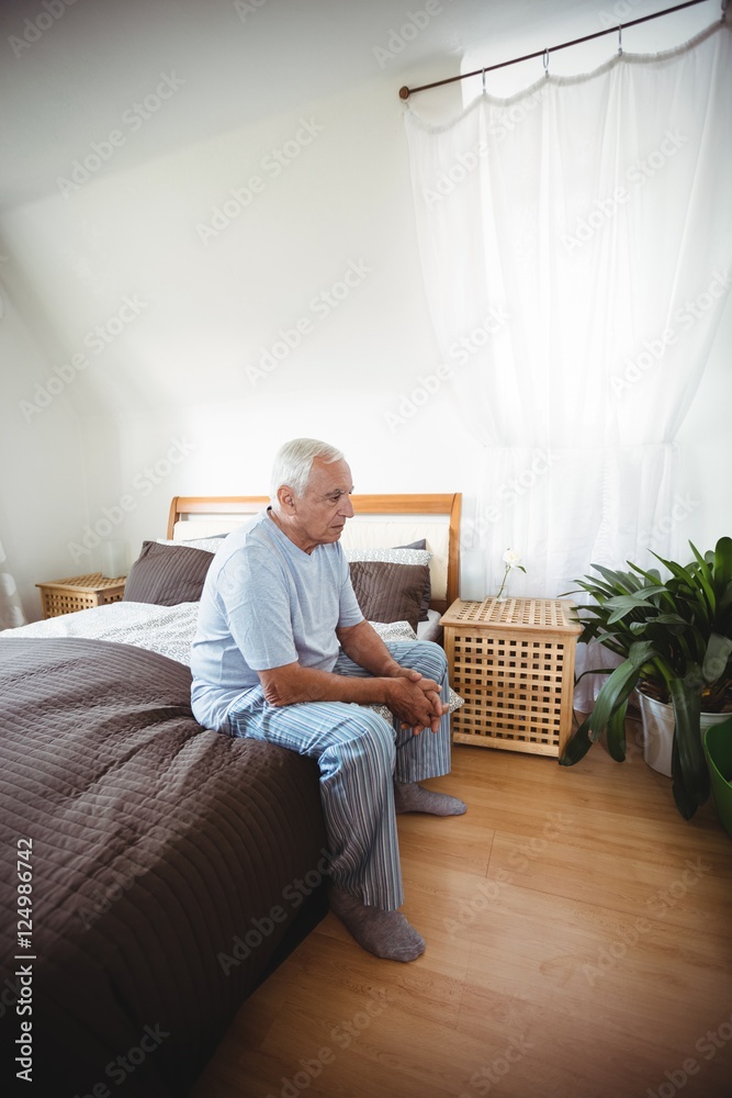 Thoughtful senior man sitting on bed