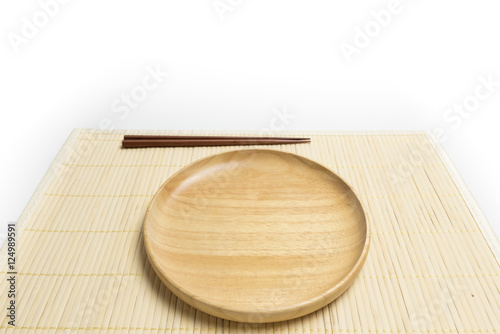 Wooden plate or tray with chopsticks place on a bamboo mat isolated on white background