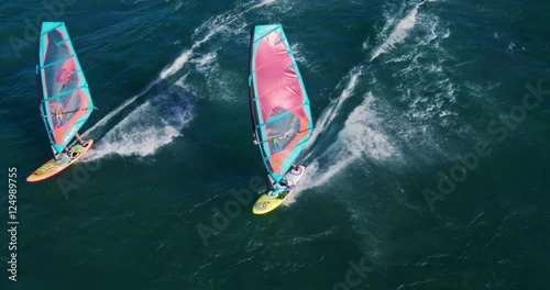 Aerial view of windsurfers gliding across blue ocean, extreme sport