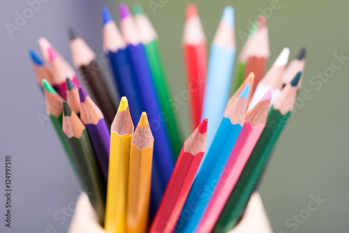 Color pencils on the table in the container with background lights. Colorful pencils in a variety of colors. Back to school concept. Closeup. Selective focus.