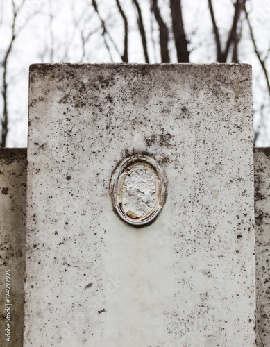 Old gravestone with damaged portrait of the buried person photo