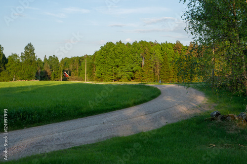 Grusväg som går genom landsbygd med åker och skog