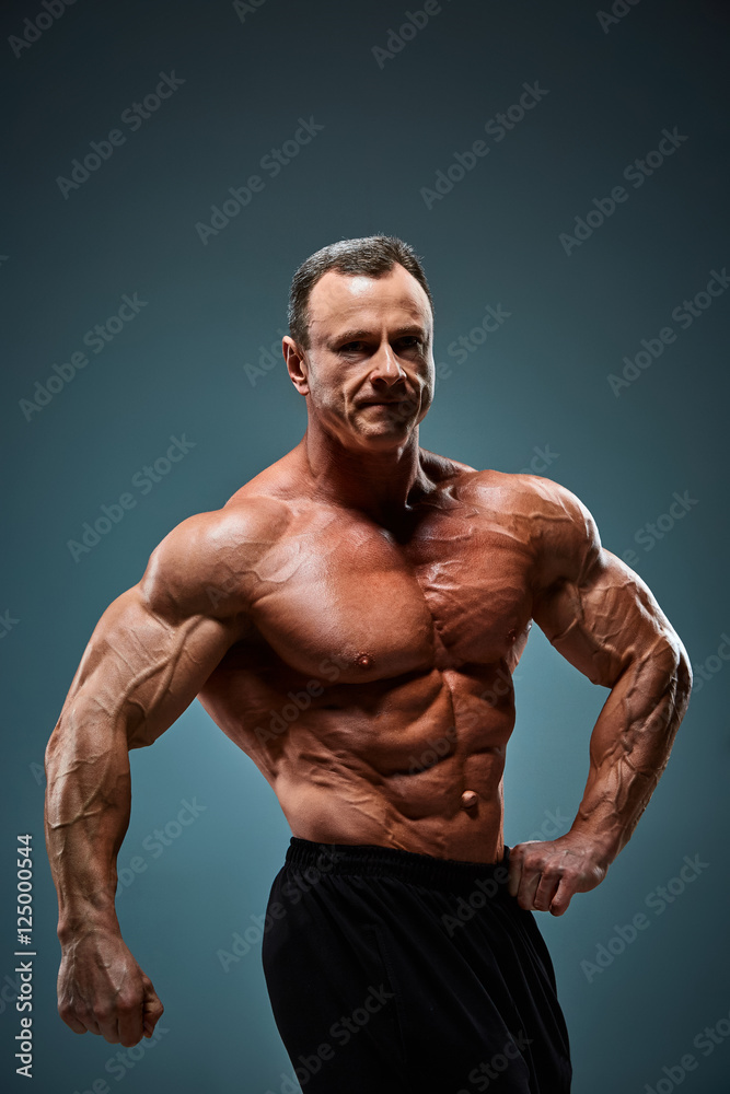 Fototapeta premium torso of attractive male body builder on gray background.