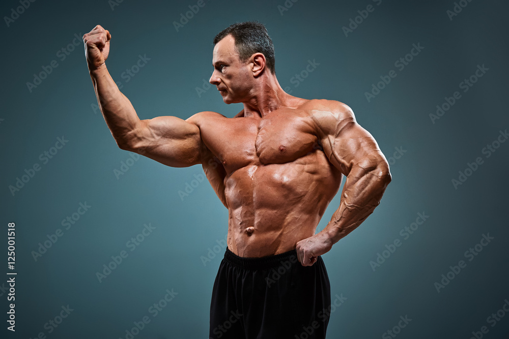 torso of attractive male body builder on gray background. torso of attractive male body builder on gray background.