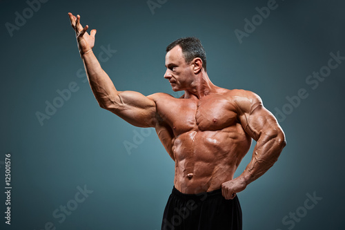 torso of attractive male body builder on gray background.
