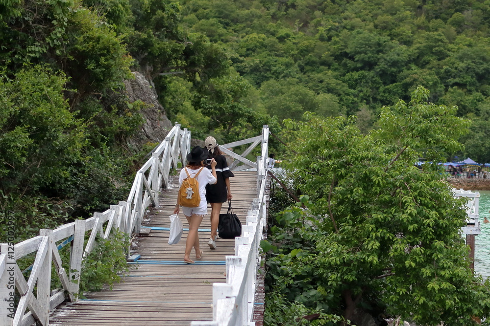 Young women backpacker walk across the white bridge.