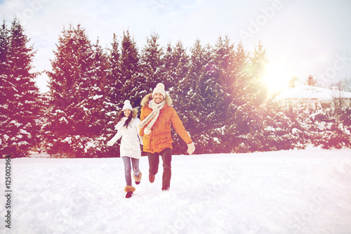 happy couple running in winter snow