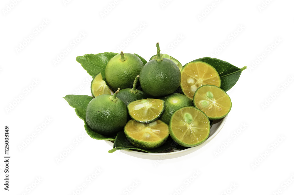 Obraz premium Cut limes and green leaves in a small bowl on white background.