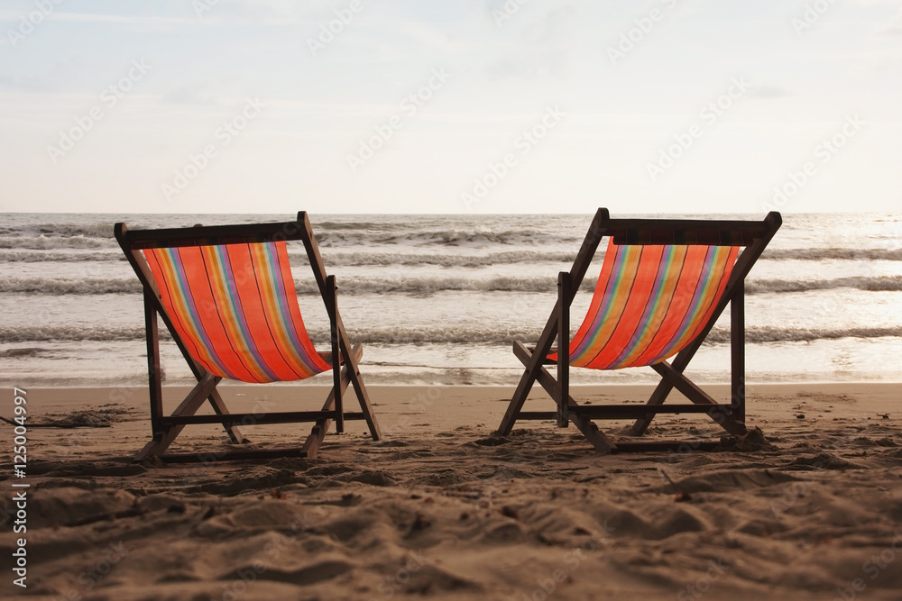 Beach holidays, couple of deck chairs at sunset