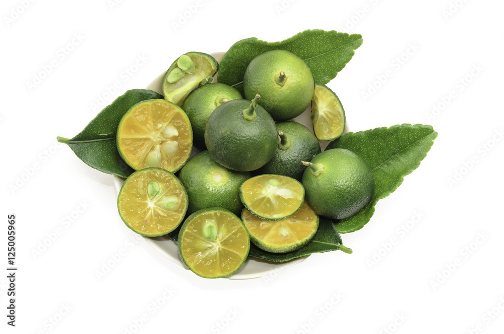 Obraz premium Cut limes and green leaves on white background.