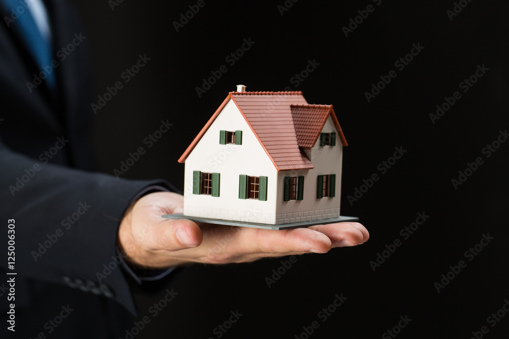 close up of businessman hand holding house model close up of businessman hand holding house model