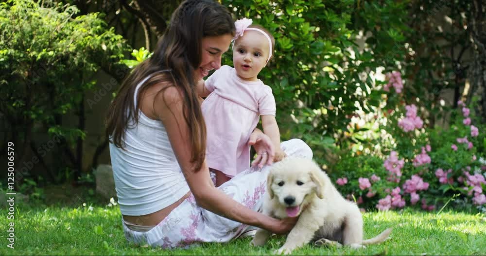 tender mother with a child playing with a sweet puppy golden retriever in a beautiful garden on a sunny day lying on the grass tender mother with a child playing with a sweet puppy golden retriever in a beautiful garden on a sunny day lying on the grass