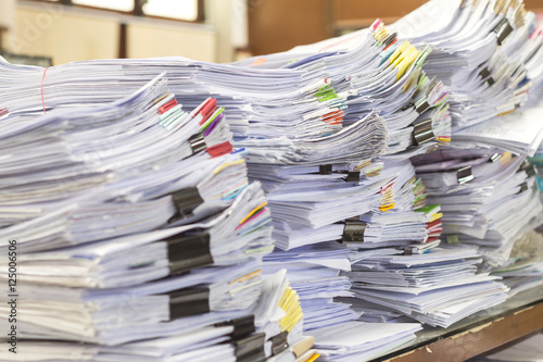 Pile of documents on desk stack up high waiting to be managed © notwaew